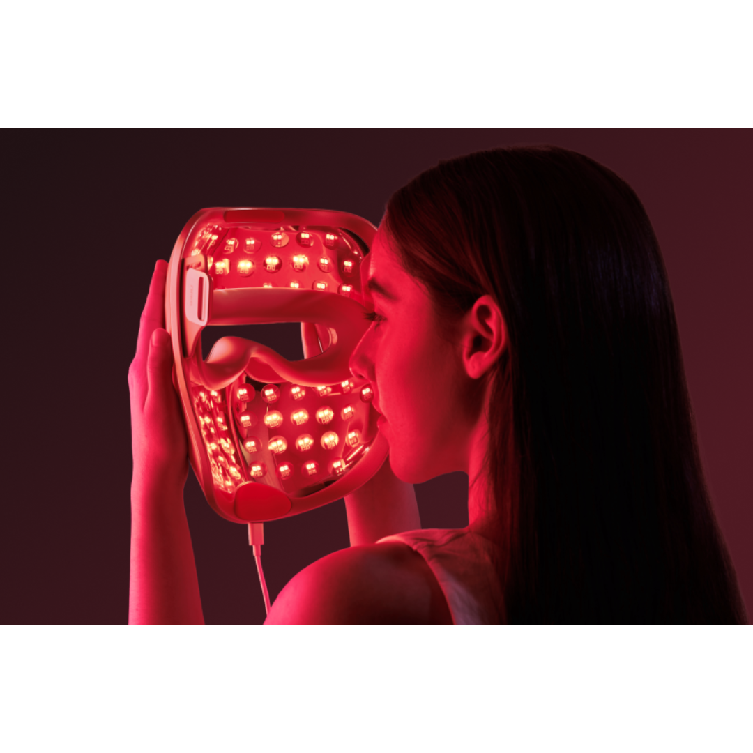 Person holding a red LED face mask against a dark background