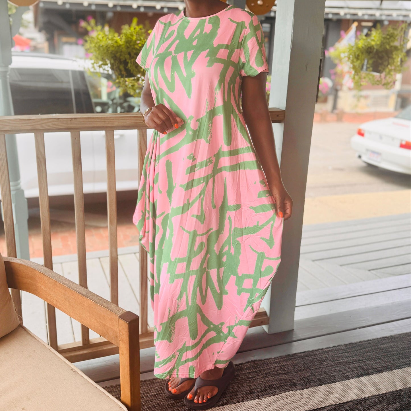 Woman in a pink and green dress standing on a porch